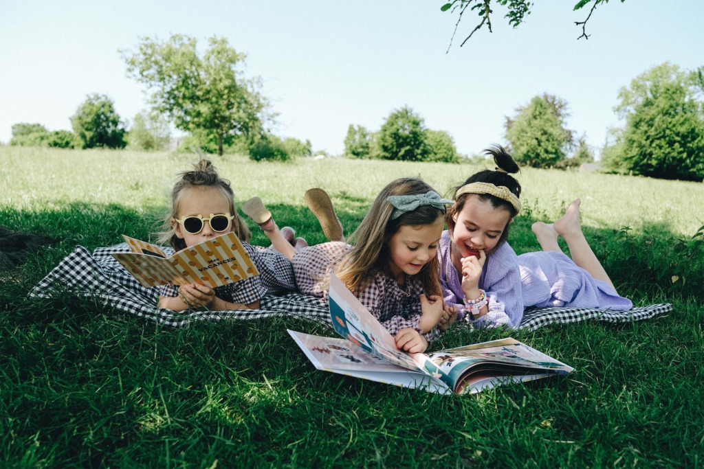 des enfants lisent leurs imagiers dans la pelouse 